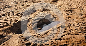 High angle shot of a small puddle on a sandy brown surface