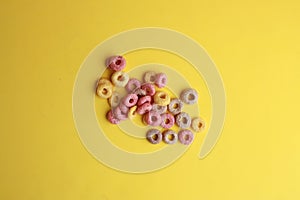 High angle shot of some colorful fruit loops isolated on a yellow surface