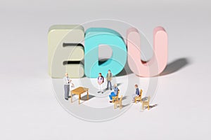 High angle shot of teacher and student figurines standing around EDU letters