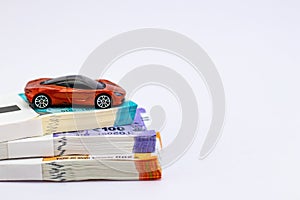 High angle shot of a toy car over money bundles against white background with copy space