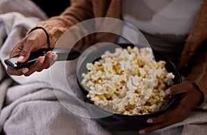 Time to binge watch your favourite show. High angle shot of an unrecognizable woman eating popcorn while watching tv at photo