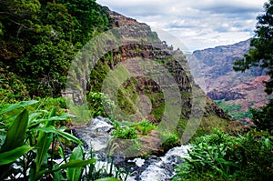 High angle shot of a waterfall flowing in the middle of a green mountainous scenery