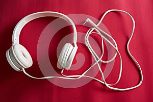 High angle shot of white wired headphones on a red surface