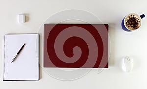 High angle shot of a work desk with a laptop, a cup of coffee, mobile phone, notepad, and headphones