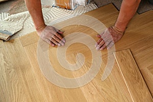 High angle shot of a worker installing wooden parquet laminate flooring