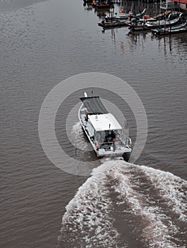 High angle speed boat moving at high speed near the fisherman village. Drone view of a boat sailing