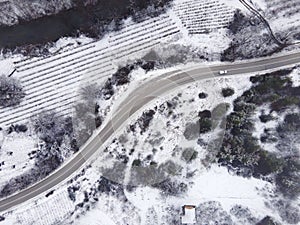 High angle top down aerial view drone image on road trough the trees and forest covered with white snow in winter day near