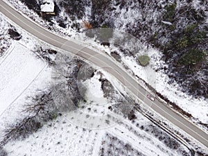 High angle top down aerial view drone image on road trough the trees and forest covered with white snow in winter day near