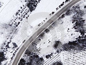 High angle top down aerial view drone image on road trough the trees and forest in mountain range covered with white snow in