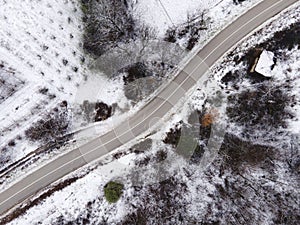 High angle top down aerial view drone image on road trough the trees and forest in mountain range covered with white snow in