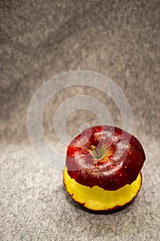 High angle vertical shot of a nearly eaten red apple on a gray fabric background