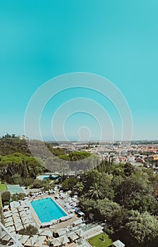 High angle vertical shot of a pool surrounded by trees with buildings in the distance