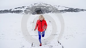 High angle view of active senior woman outdoors in snowy winter, running.