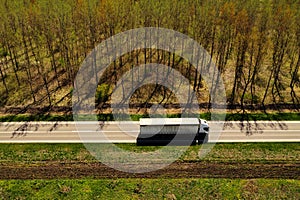 High angle view aerial shot of semi-truck on highway with wooded landscape in background