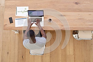 High angle view of african american man sitting at table using laptop working from home