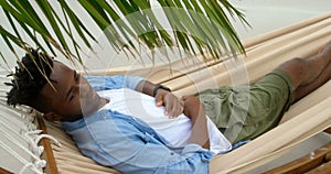 High angle view of African american man sleeping in a hammock at beach 4k