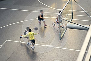 High angle view of Asian children playing basketball outdoors at sunset