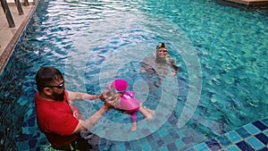 High angle view of asian family having fun in swimming pool outdoors. Active kids.