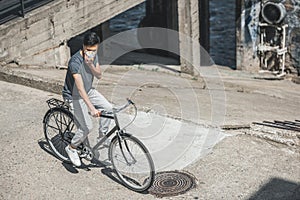high angle view of asian teen in protective mask riding bicycle on bridge air