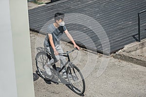 high angle view of asian teen in protective mask riding bicycle in city air