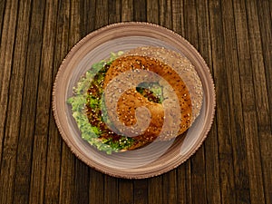 High-angle view of an avocado bagel in a plate on the wooden surface