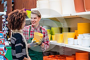 Customer buying plastic pots at the advice of a helpful worker in flower shop