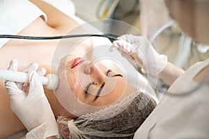 High angle view of beautiful young woman having Radio frequency skin tightening treatment in beauty clinic.