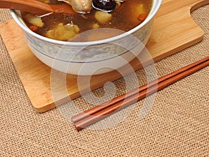 High angle view of a bowl of chicken soup. It contain Chinese medicine such as goji berry and red jujube.