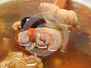 High angle view of a bowl of chicken soup. It contain goji berry and red jujube.