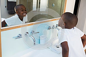 High angle view of boy clenching teeth while looking at mirror