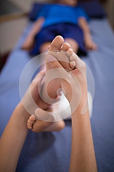 High angle view of boy receiving foot massage from female therapist while lying on bed