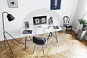 High angle view of a bright home office interior for a creative professional with black and white furniture and herringbone parque