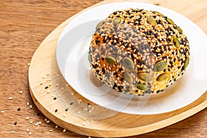 High angle view of burger bun sprinkled with white and black sesame and pumpkin seeds
