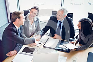 High angle view of businessmen shaking hands in conference room