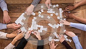 High Angle View Of Businesspeople Solving Jigsaw Puzzle