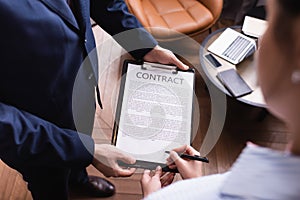 High angle view of businesswoman singing contract near businessman during meeting in restaurant.