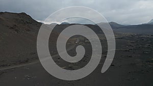 High angle view car driving peacefully through desert remote dust road in icelandic highlands. Drone view 4x4 suv