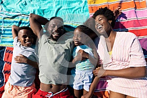 High angle view of cheerful african american parents and children resting on towels at beach