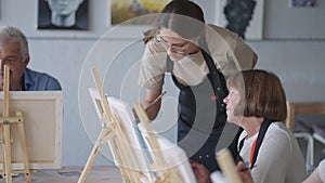 High angle view of cheerful senior friends painting on canvas. Senior woman smiling while drawing with the group