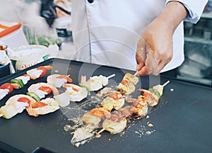 High angle view of chef cooking fresh shrimp BBQ on flat hot plat with one hand holding