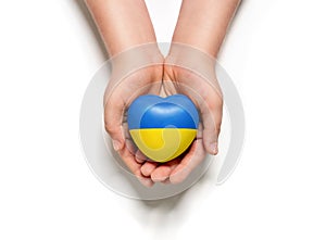 High angle view of child hands holding ukraine flag painted heart