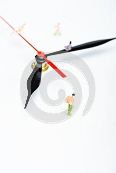 High angle view of clock arrows and plastic people figures on white surface