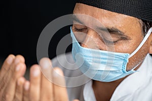 High angle view close up shot of muslim man in medical mask preforming Salah or prayer by closing eyes. photo