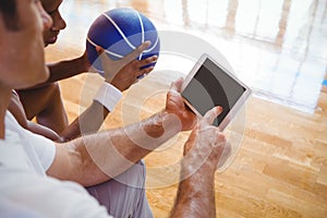 High angle view of coach showing digital tablet to basketball player