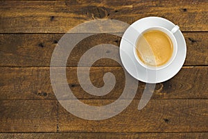 High angle view of coffee in white cup with saucer on old wooden background, close up