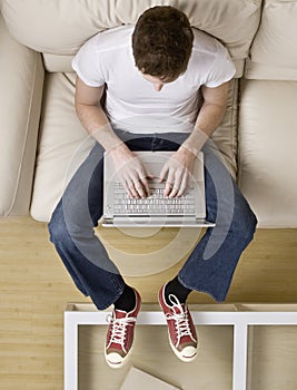 High angle view of cool young man typing on laptop