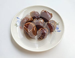 High angle view of dates in a plate on a white background.