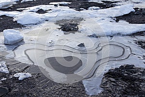 High angle view of detail of ice melting and forming whorl patterns on rocky beach photo