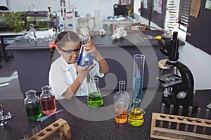 High angle view of elementary student examining blue chemical in flask at laboratory