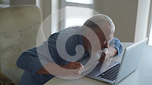 High-angle view of exhausted unhappy senior aged man with gray-haired beard feeling strong back ache after sitting at